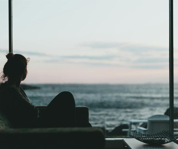Calm person looking attentively towards a light source in a serene room.